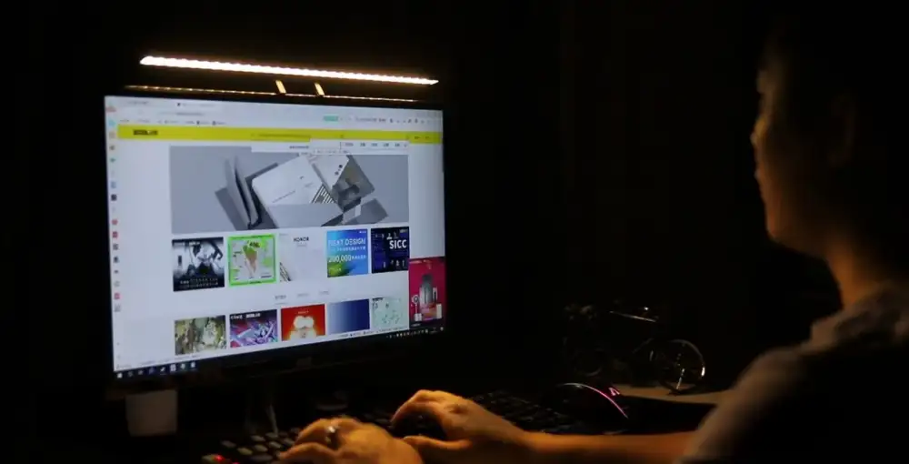 A workspace setup image showing the webcam mounted atop a laptop or monitor with the desk light on,