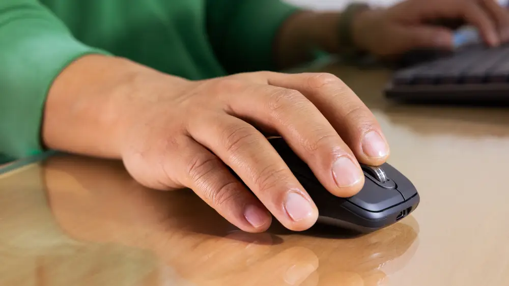 Logitech MX Anywhere 3S Wireless Mouse hand using Logitech MX Anywhere 3S wireless mouse on desk showing compact ergonomic design