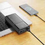 Hoco power bank charging a smartphone while placed on a laptop keyboard