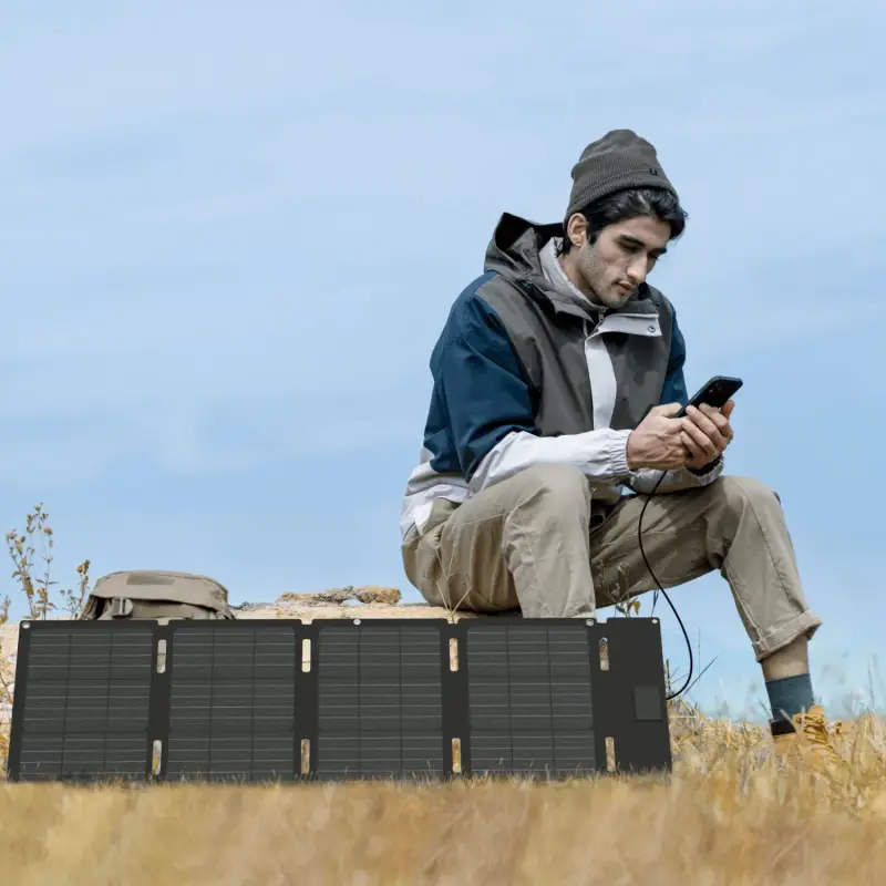 EcoFlow 45W Portable Solar Panel for Camping & Outdoor Charging Person using the EcoFlow 45W Portable Solar Panel outdoors to charge a smartphone during camping.